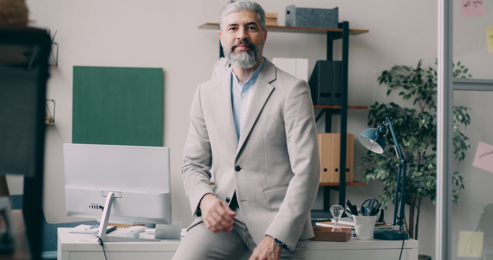 Man in een licht pak bij een bureau in een modern kantoor